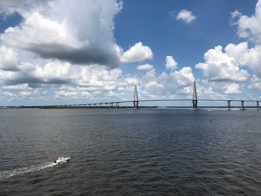 bridge crossing a large river with boat in the foreground