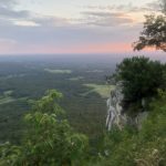 sunset past a cliff with trees at the top
