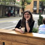 Woman sitting at wooden table with coffee at one of the best coffee shops in Winston-Salem.