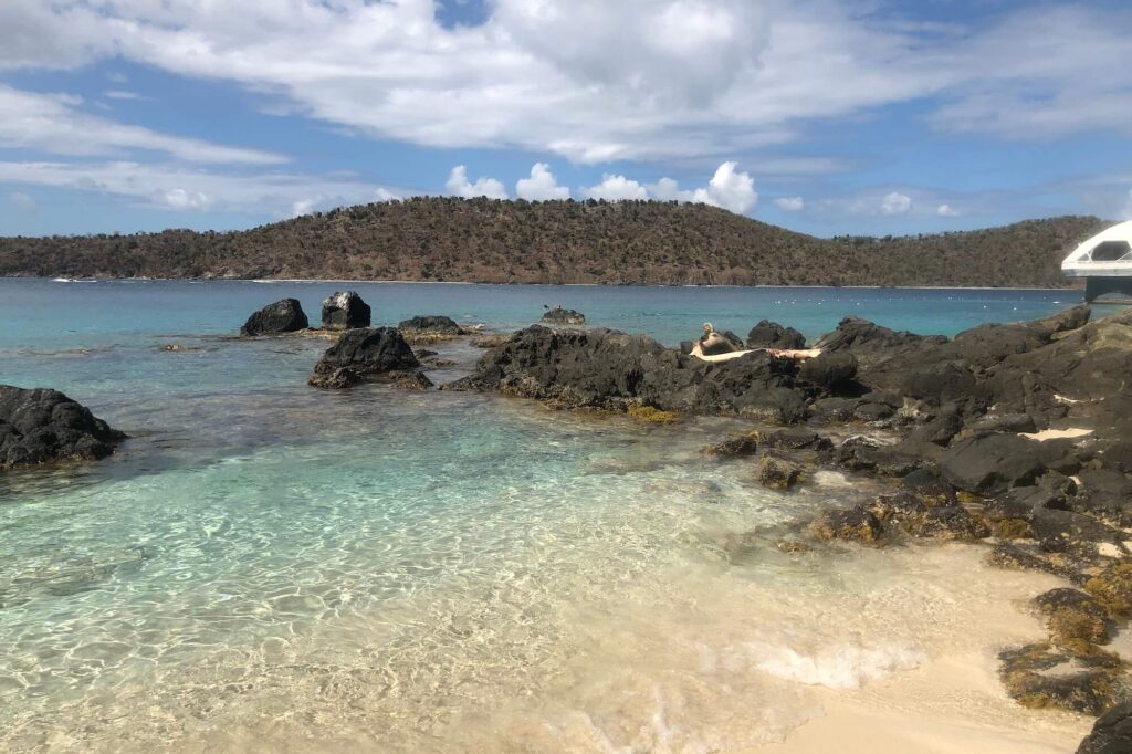 Beach with rocky area and mountain in the background.