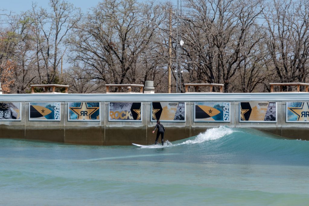 Girl standing up on a surfboard in a wave pool at Waco Surf. This tourism board pitch template can help you land partnerships like this.