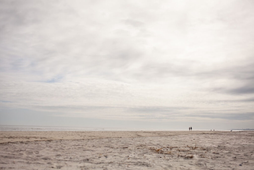 People in the distance walking along a beach on a cloudy day. It's Isle of Palms, the closest beach to Asheville.