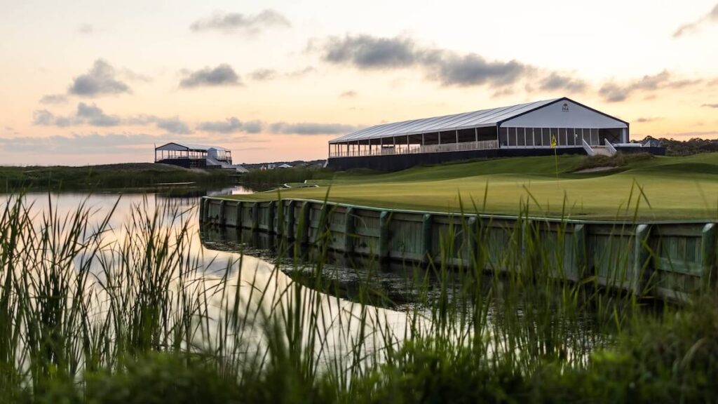 Golf course and pavilion right next to the water at sunset.