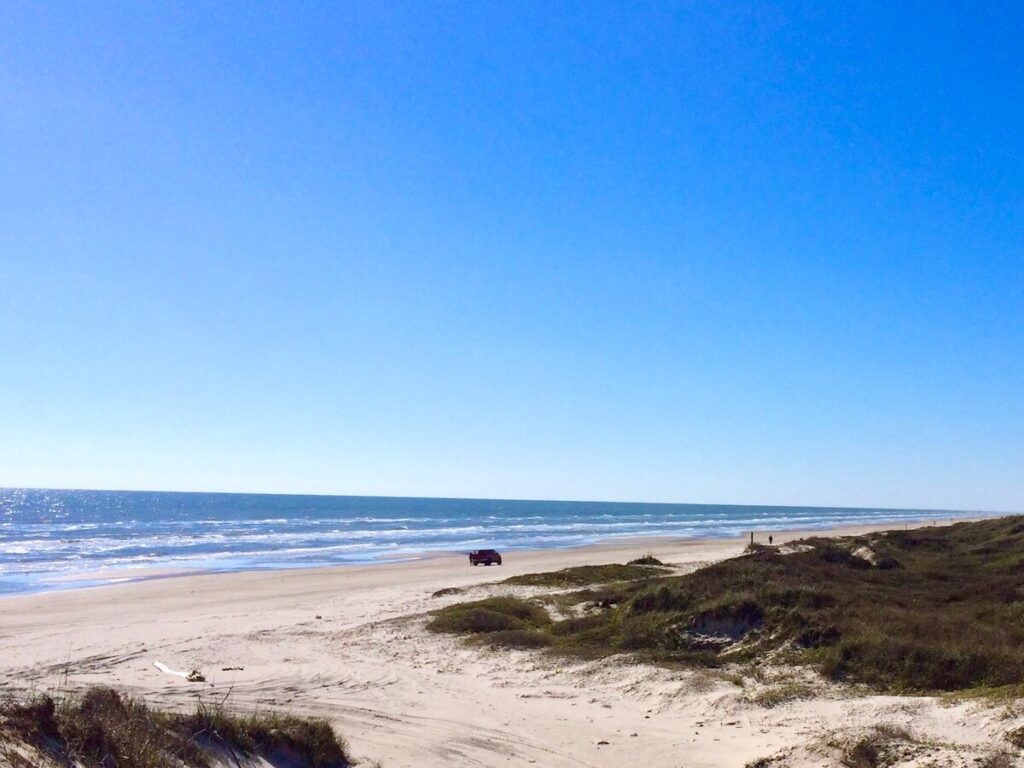 Car driving past the dunes along one of the best beaches near Houston.