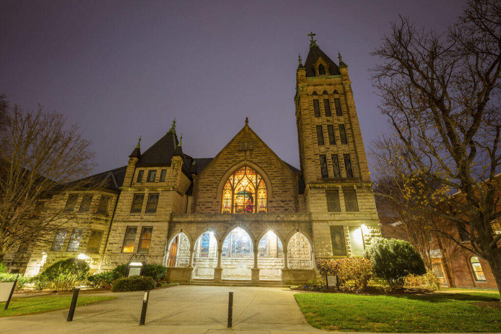 Large church with stone facade lit up at night.