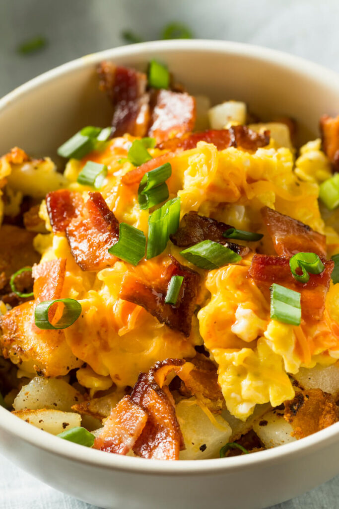 Breakfast bowl with eggs, cheese, bacon, and potatoes.