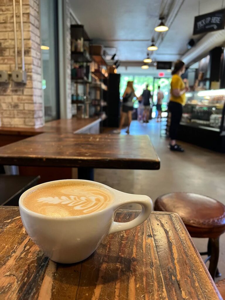 Latte on the table with people ordering in the background.