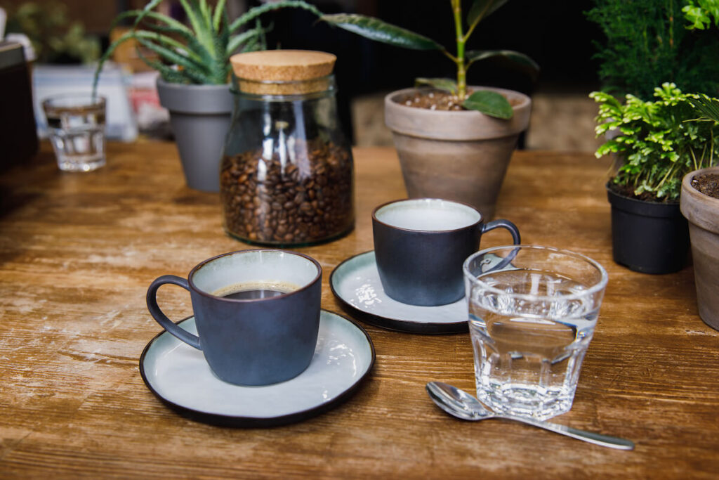 Coffee mug and water sitting on a table with other plants.