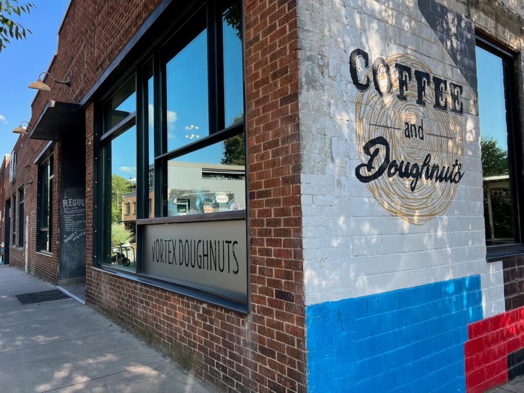 Brick building with mural that says Coffee and Doughnuts at one of the best Asheville coffee shops.