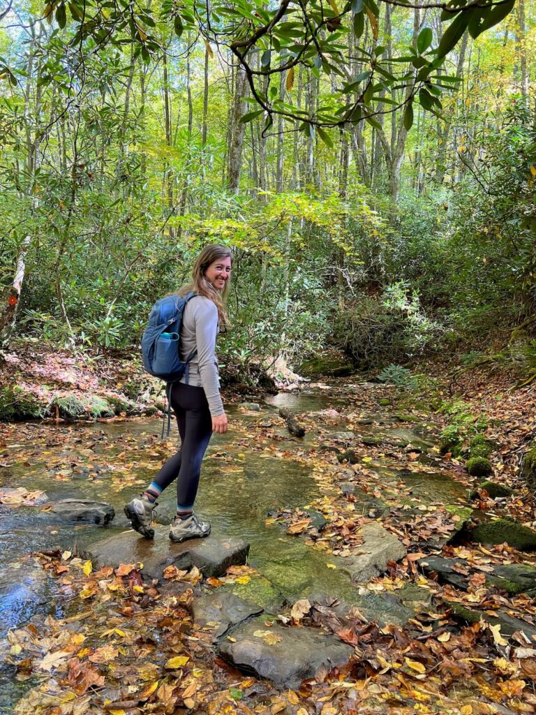 girl standing on a rock in the river with a hiking pack on