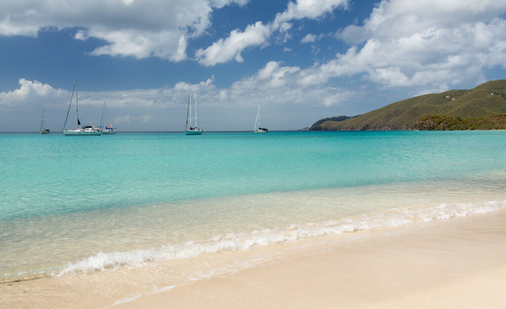 Gentle waves rolling on a St. Thomas beach with boats in the distance
