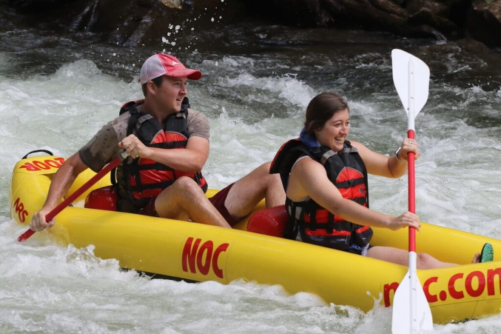 man and woman paddling in two person raft