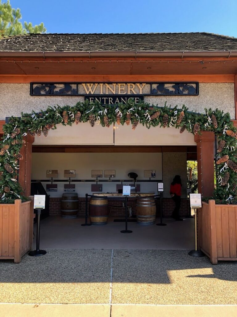 Sign that says "Winery Entrance" over the arched doorway to the winery. Christmas garland is hung over it.