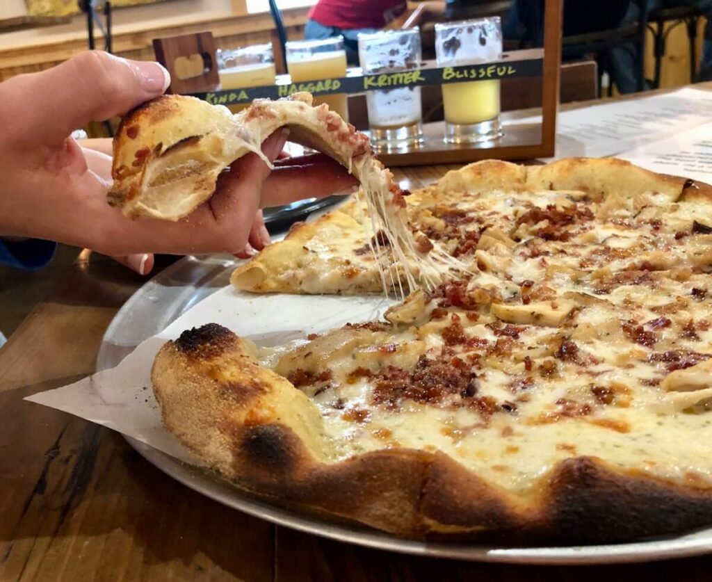 Woman's hand pulling a slice of pizza from the pan.