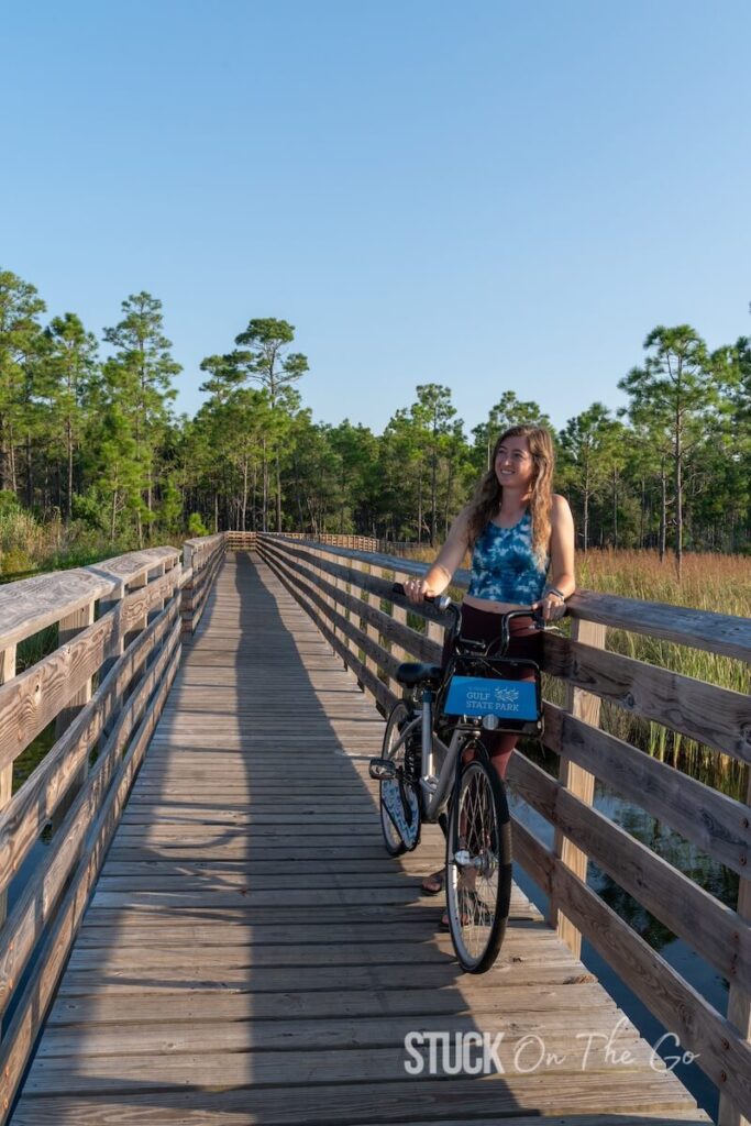 girl standing on boardwalk holding a bike