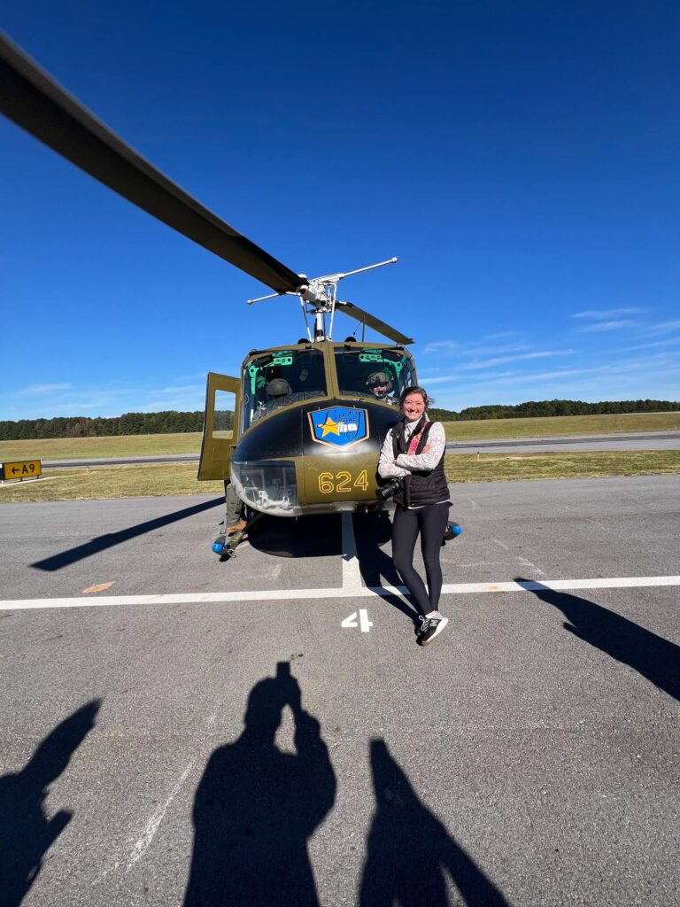 What is a press trip - Anna leaning on a army helicopter courtesy of the Army Aviation Heritage Foundation.