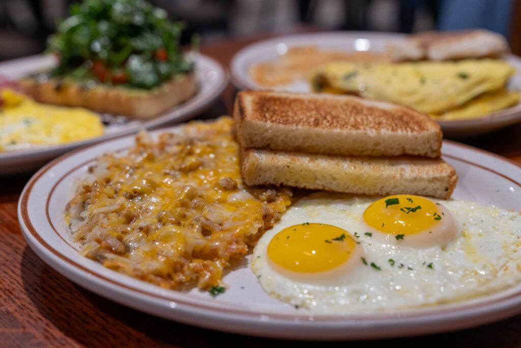 eggs, hashbrowns, and toast on the tabel with other breakfast items in the background