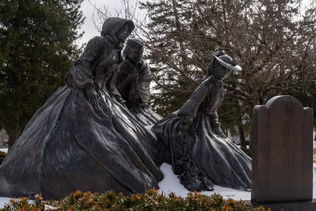 statue of three women visiting their father's grave
