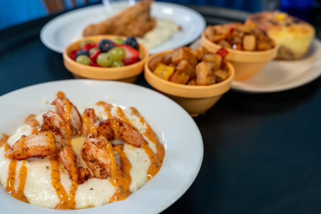 bowl of shrimp & grits with some other food in the background