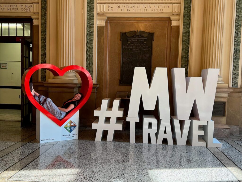 Girl posing in the heart component of the Midwest Travel Network Conferences, which focuses on destinations across the Midwest US.