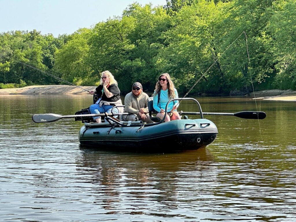 Friends in a dinghy fishing on a large river.
