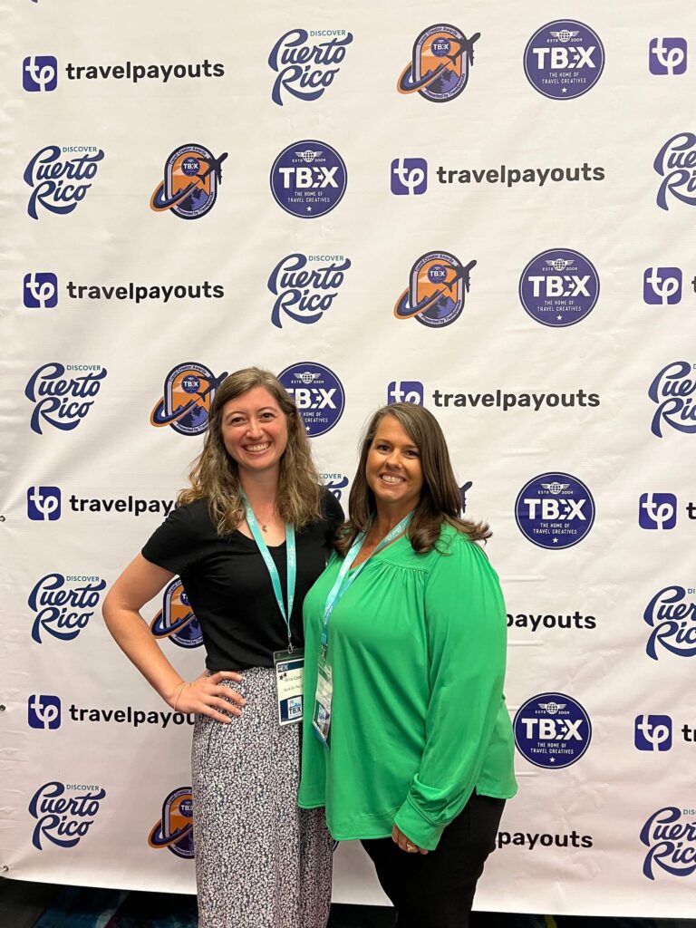 Ladies posing in front of the conference banner at TBEX, one of the most well-known travel blogging conferences.